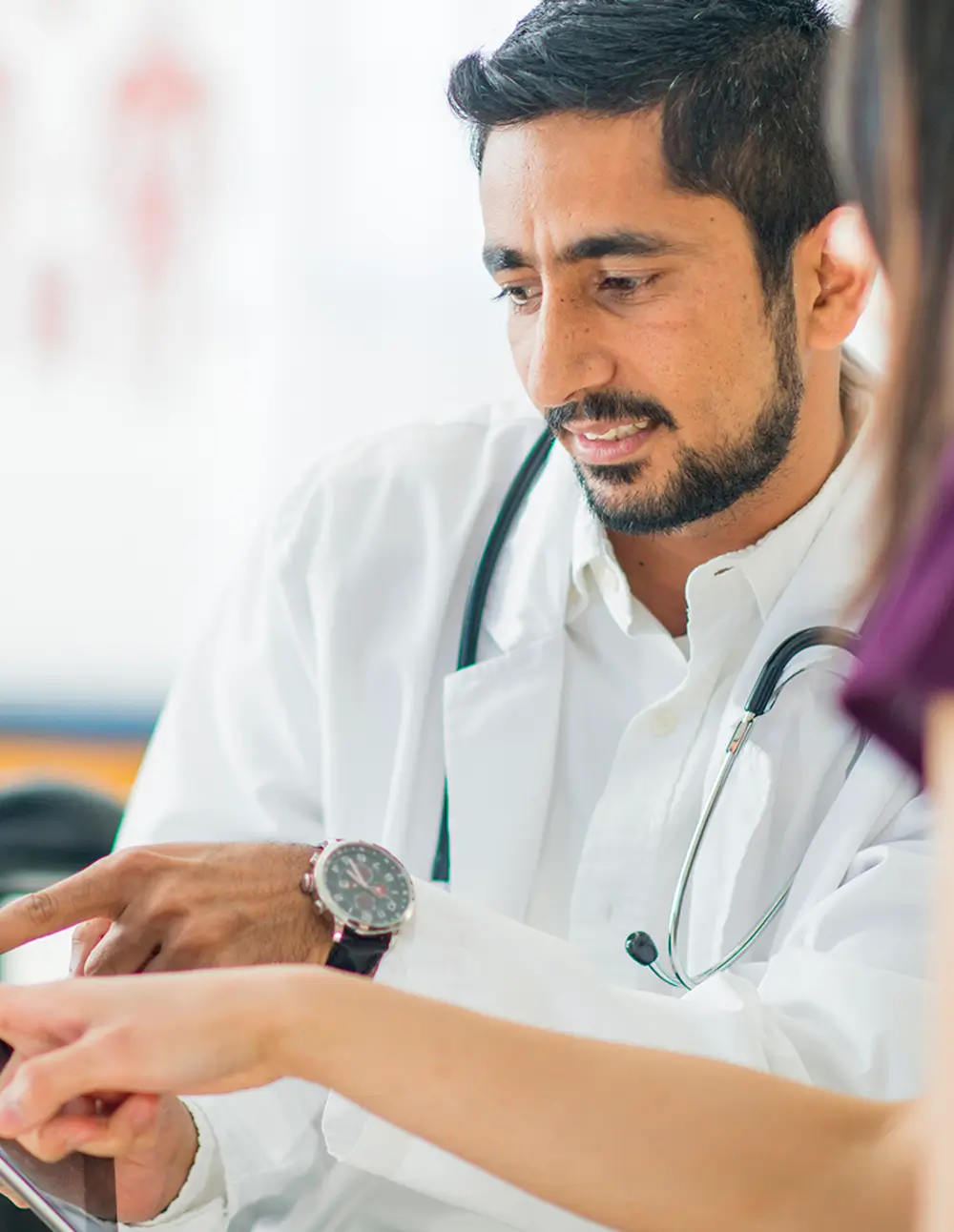 Doctor pointing at a tablet screen while consulting a patient