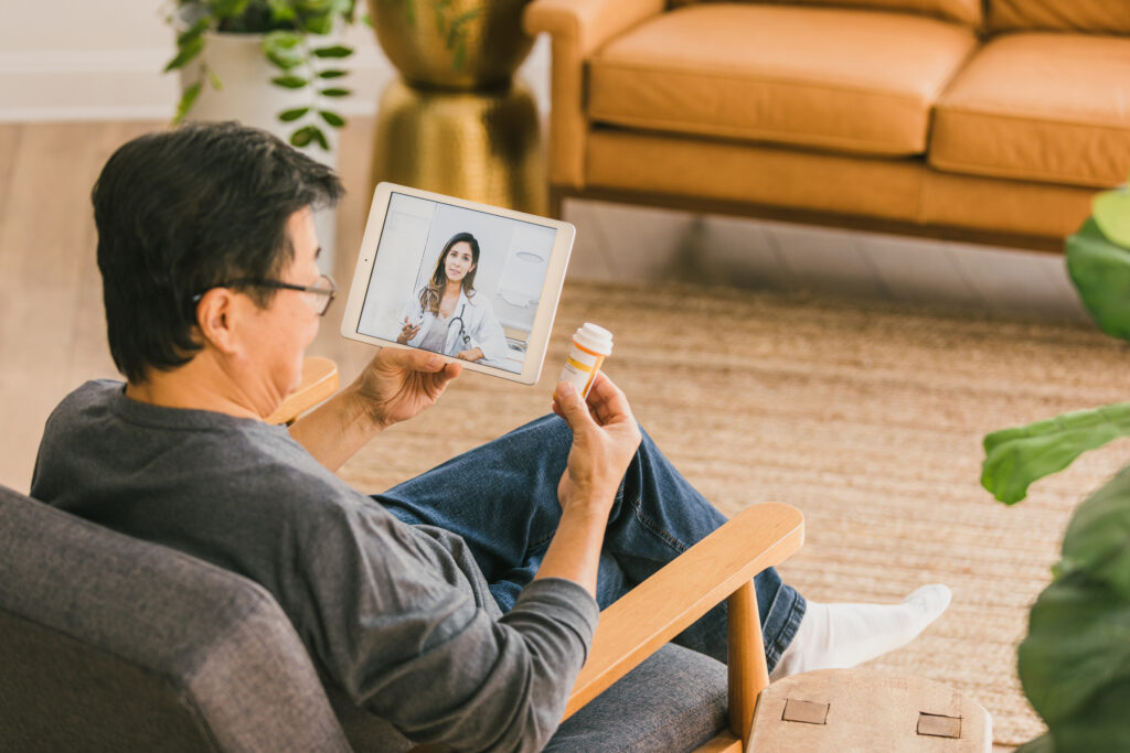 Man having a telehealth appointment while holding a pill bottle and discussing blood sugar
