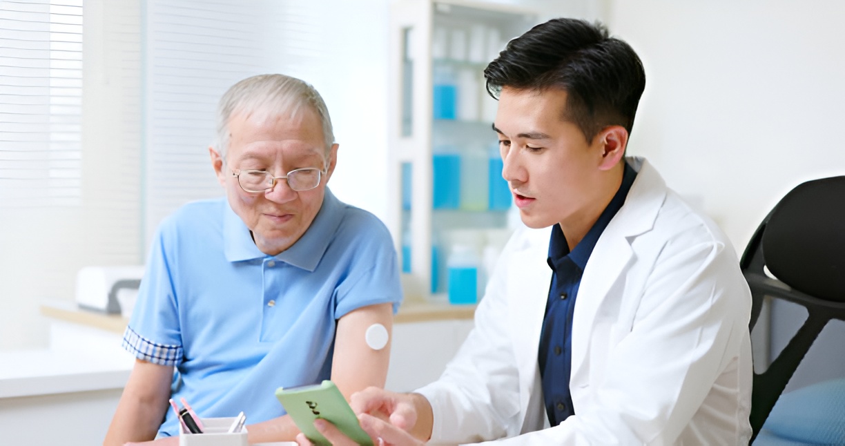 Older man with a CGM reviewing blood sugar data with a doctor