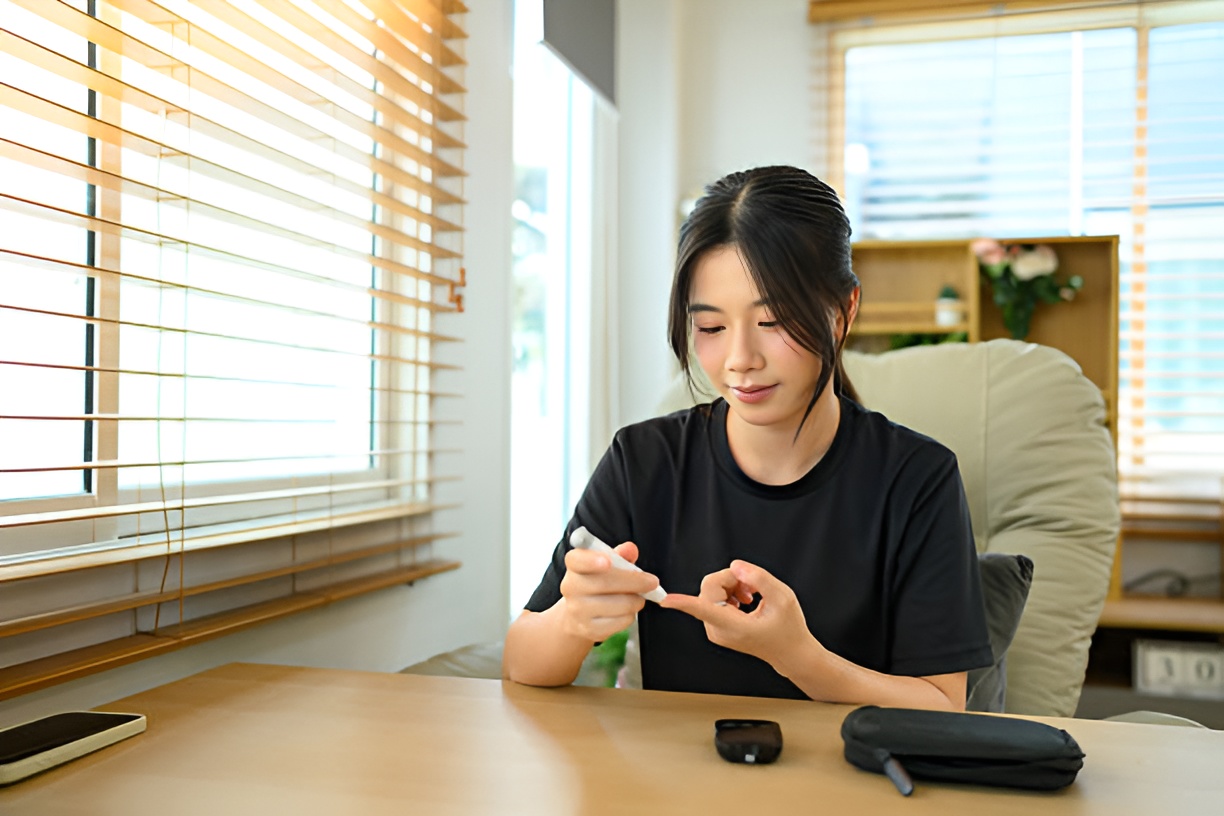 Woman checking blood sugar at home to monitor HbA1c levels