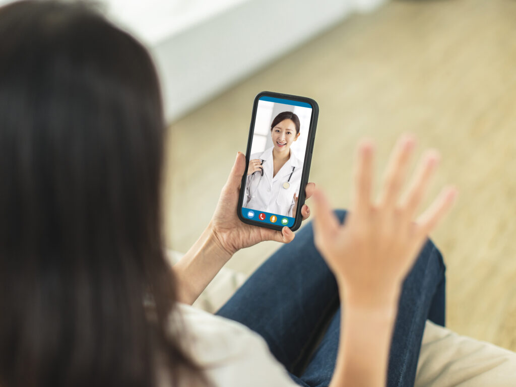 Woman waving to a doctor on a smartphone during a diabetes online appointment